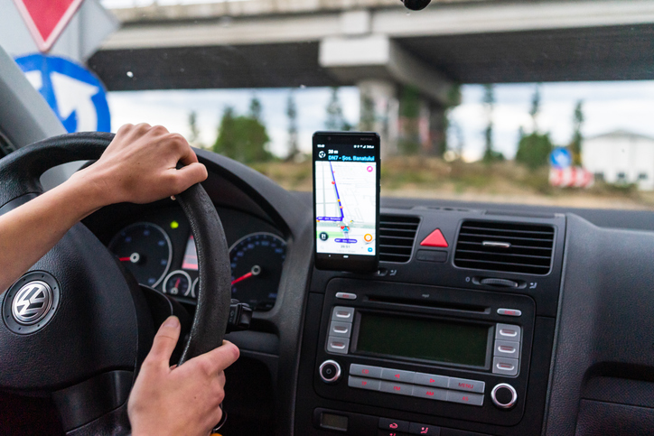 Driving And Using Waze Maps Application On Smartphone On Car Dashboard